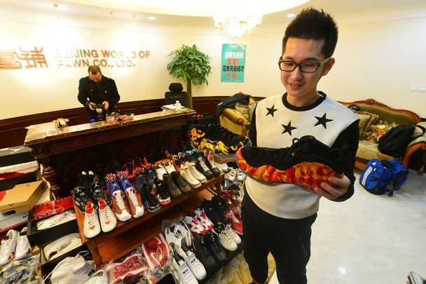 Il trentenne cinese Mick, proprietario di 283 paia di scarpe da ginnastica Nike Jordan, guarda le scarpe che ha impegnato per pagare un acconto su un appartamento presso il banco dei pegni di Beijing World of Pawn Co., Ltd. a Pechino, Cina, 9 febbraio 2015
 - Foto, immagini