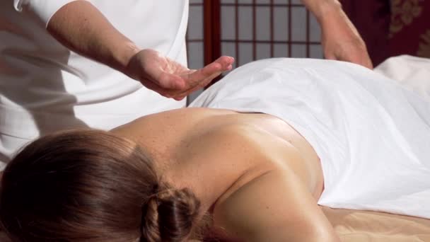 Masajista profesional aplicando aceite a la espalda de su cliente, preparándose para masajear
 - Metraje, vídeo
