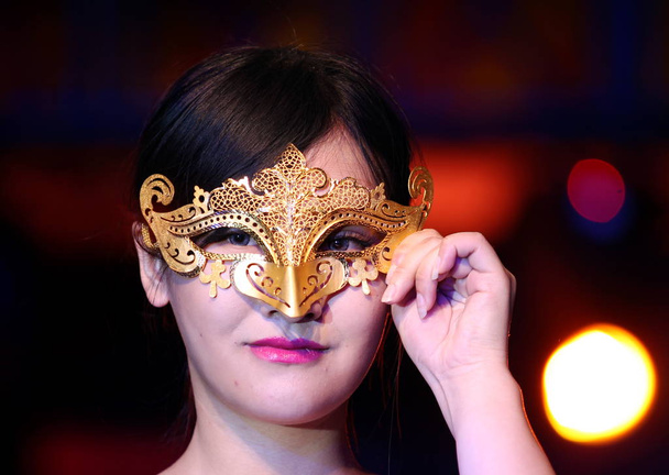 A model displays a gold mask at a dealer conference of Chinese jewelry brand Mokingran in Xi'an city, northwest China's Shaanxi province, 2 April 2015 - 写真・画像