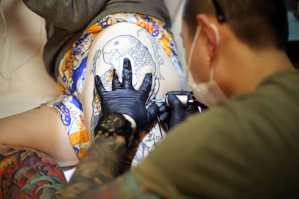 Κινεζική τατουάζ καλλιτέχνης Wang Wenbin μελάνια στο μηρό του πελάτη σε ένα στούντιο τατουάζ στη Σαγκάη της Κίνας, 29 Μαρτίου 2015 - Φωτογραφία, εικόνα