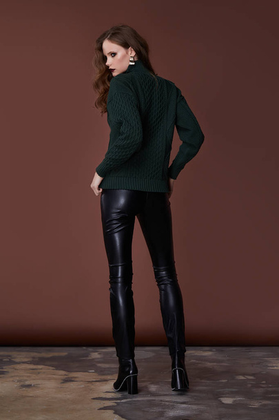 Sexy beautiful woman fashion glamour model brunette hair makeup wear knitted sweater black lather trousers clothes  every day casual party style jewelry date walk girlfriend skinny body shape studio. - 写真・画像