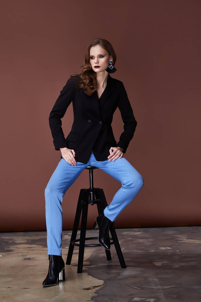 Beautiful sexy young business woman dark hair evening makeup wearing formal suit jacket blue pants high heels shoes business clothes for meetings walks collection perfect body shape chair. - Fotoğraf, Görsel