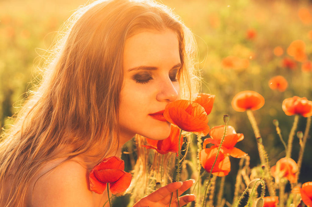 Hermosa chica en el campo oliendo flor de amapola
 - Foto, Imagen