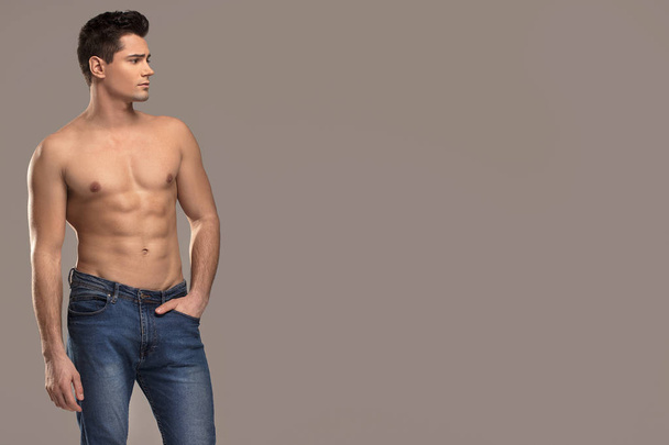 Beautiful sporty guy. Man with muscular torso posing only in jeans. Studio shot. - Foto, Imagem