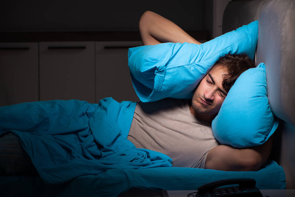 Ένας άνθρωπος κουρασμένος εξαντλήσει στον ύπνο στο κρεβάτι του - Φωτογραφία, εικόνα