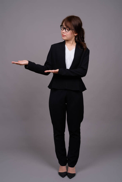 立っている若いアジア女性実業家の完全な長さの肖像画 - 写真・画像