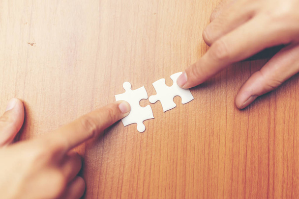 Pohled z vysokého úhlu podnikatelé ruky řešení Jigsaw Puzzle na dřevěné desce - Fotografie, Obrázek