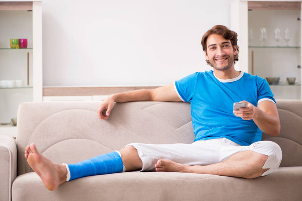Leg injured young man on the sofa - Fotoğraf, Görsel
