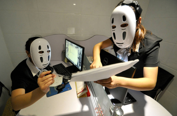 Dipendenti del fornitore di servizi per ufficio cinese Oxford Office Building che indossano maschere per sfogare lo stress parlano alle loro scrivanie nell'ufficio nella città di Handan, nella provincia di Hebei, nel nord della Cina, 14 luglio 2015
 - Foto, immagini