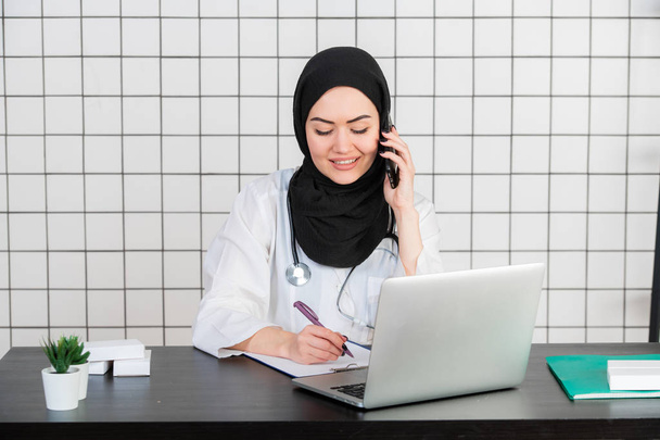 Portret van prachtige islamitische vrouwelijke arts met behulp van mobiele telefoon - Foto, afbeelding