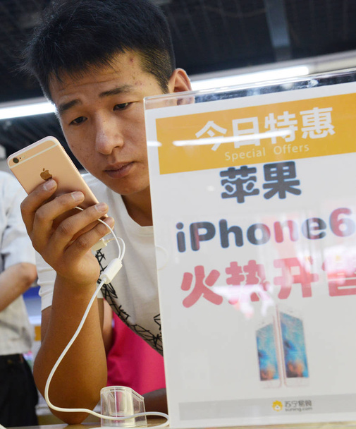 A customer tries out a rose gold iPhone 6s smartphone at an Apple store in Zhengzhou city, central China's Henan province, 25 September 2015 - Фото, изображение