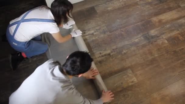 muž a žena chrání podlahu s plastovou fólií pro renovaci domů - Záběry, video