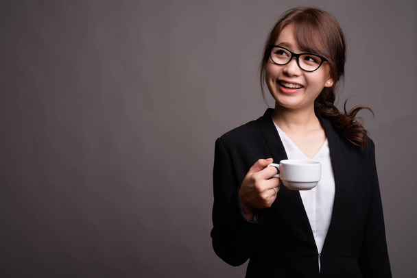 Junge schöne asiatische Geschäftsfrau mit Kaffeetasse - Foto, Bild