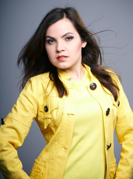 Attractive young woman in a yellow jacket. Hair in motion. - Photo, Image