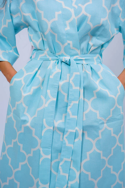 Cotton bathrobe. Textile. Bathrobe light blue with a print. The texture of the fabric. Cotton. Robe belt People. Clothes for hotels and hotels. Woman. Blonde hair. Arm. - Photo, Image