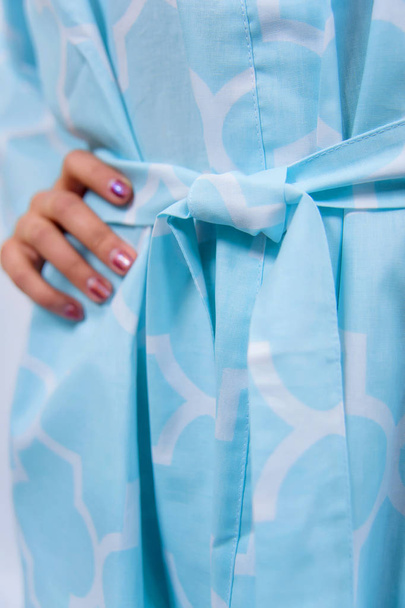 Cotton bathrobe. Textile. Bathrobe light blue with a print. The texture of the fabric. Cotton. Robe belt People. Clothes for hotels and hotels. Woman. Blonde hair. Arm. - Foto, Bild