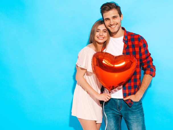 Portrait of Smiling Beautiful Girl and her Handsome Boyfriend holding  heart shaped air balloons and laughing. Happy Family. Love. Happy Valentine's Day. Isolated on blue wall - Foto, afbeelding