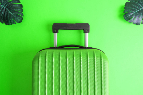 Suitcase with tropical monstera leaves on green background minimal creative travel concept. - Foto, Bild