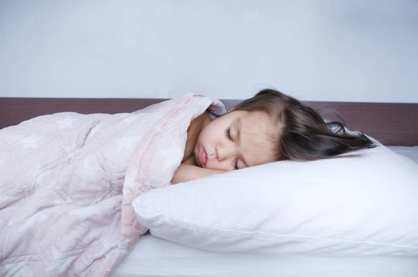 女の子はベッドに横たわって眠っています。国内のライフ スタイルで睡眠のスケジュール。かわいい赤ちゃん子供  - 写真・画像