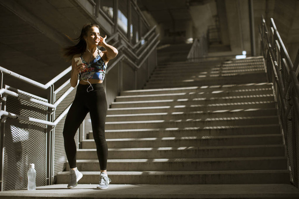 Young fitness woman doing exercises outdoor in urban enviroment - Photo, image