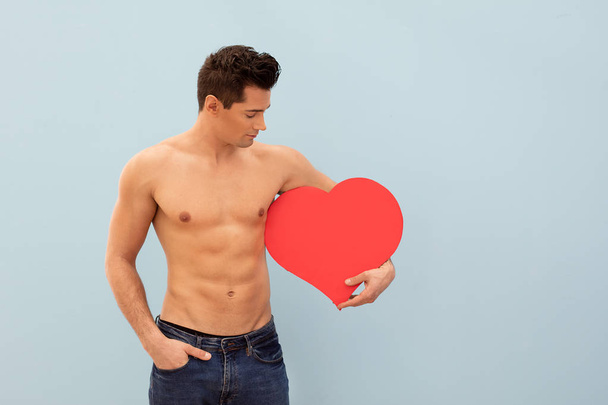 Handsome shirtless man posing with red heart, valentines day. - 写真・画像