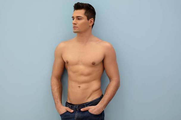 Handsome shirtless man posing on blue pastel background. - Foto, immagini