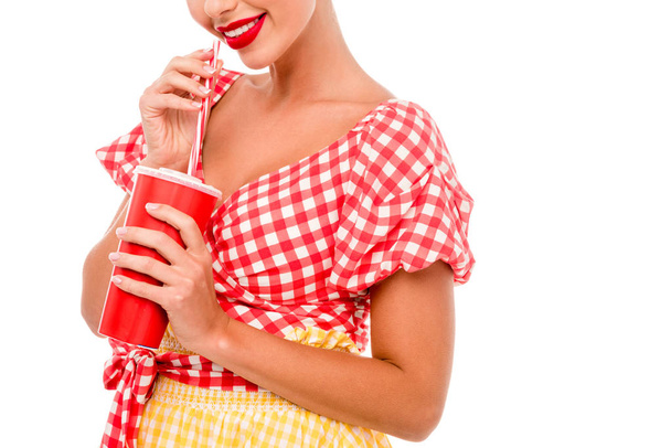 Partial view of pin up girl drinking from red disposal cup with straw isolated on white - Photo, Image