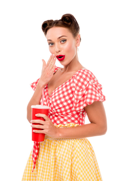 Mujer joven con taza desechable sosteniendo la mano cerca de la boca aislada en blanco
 - Foto, Imagen