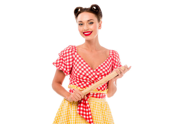 Smiling stylish pin up girl holding rolling pin and looking at camera isolated on white - Photo, Image