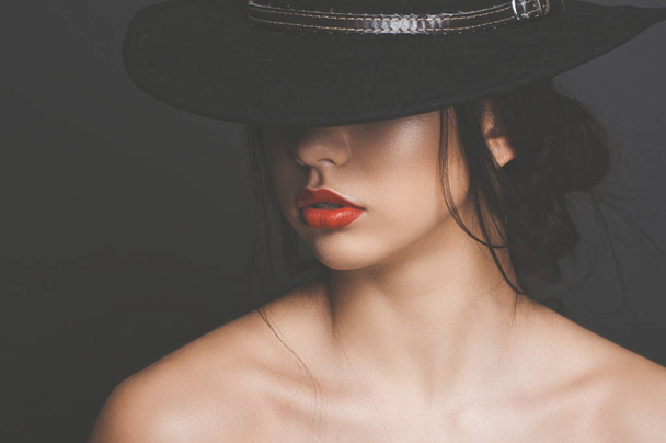 Beautiful girl with dark hair in a black hat and red lipstick - Photo, Image