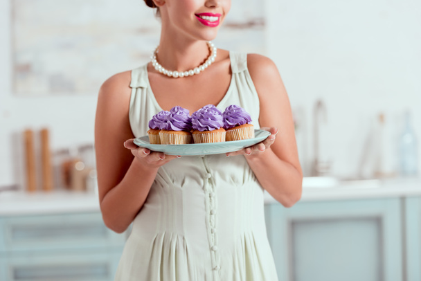 Vista parziale di pin up dorato piatto di tenuta di cupcake
 - Foto, immagini