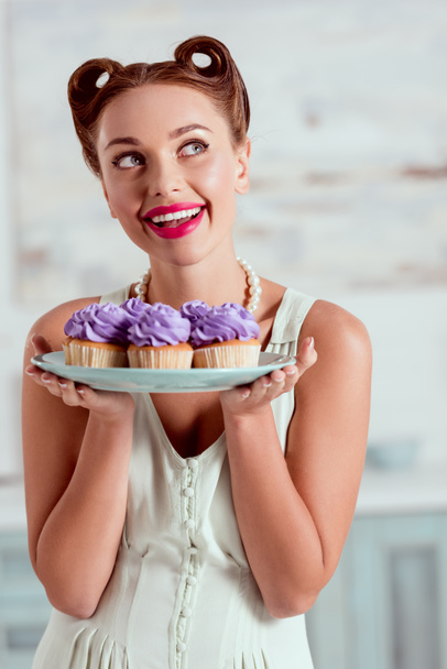 felice perno sorridente su doratura che tiene il piatto di cupcakes
 - Foto, immagini