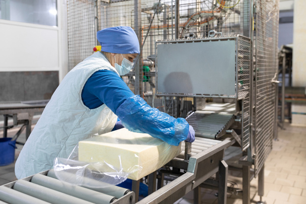 Εργαζόμενος πακέτα βούτυρο στο εργοστάσιο γαλακτοκομικών προϊόντων - Φωτογραφία, εικόνα