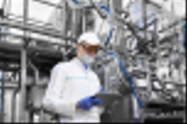 Человек в маске и халате стоит с табличкой в руках на молочном заводе
 - Фото, изображение