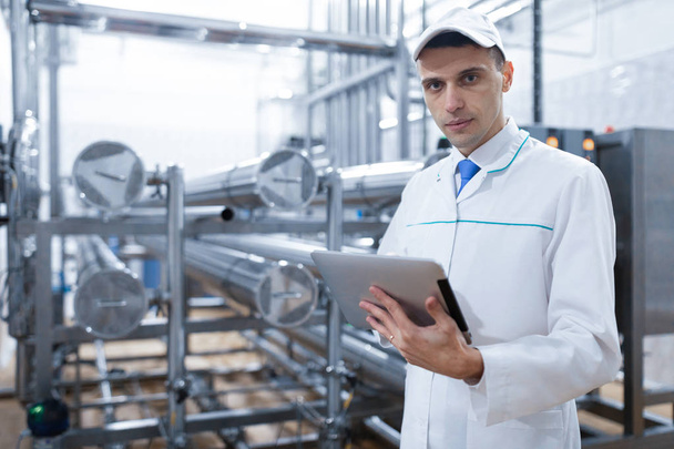 Tecnólogo con una tableta en las manos en la planta láctea
 - Foto, imagen