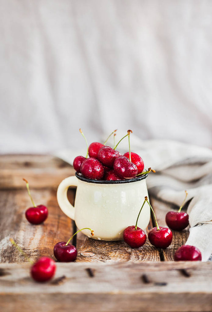 Fresh ripe cherries in a mug on rustic backgroun - Foto, Bild