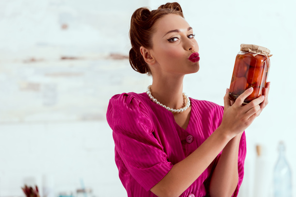 Pretty pin up girl holding canned tomatoes and sending air kiss - Fotoğraf, Görsel