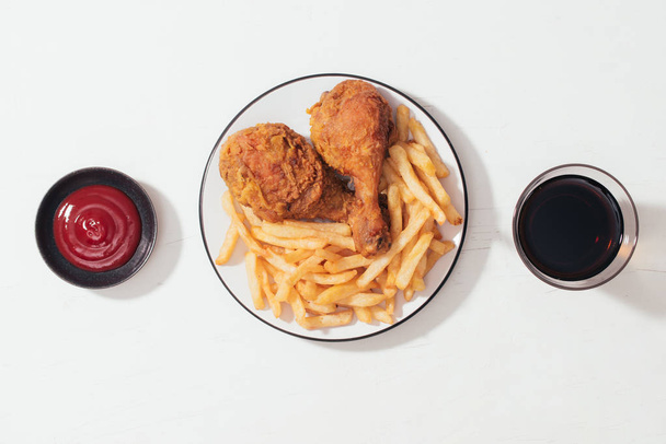 Fried breaded crispy chicken nuggets with French fries on wooden plate, ketchup and soft drink on the side - Фото, изображение