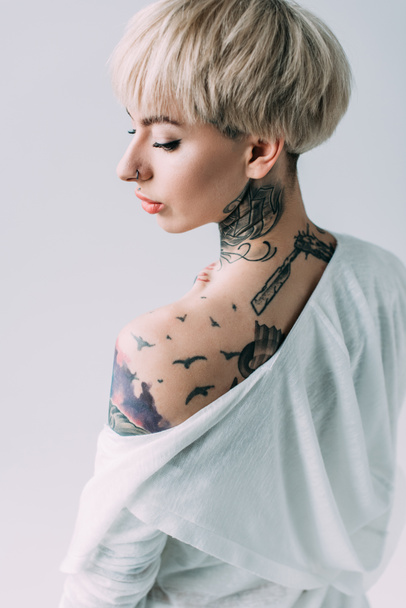 attraente donna con tatuaggi sul retro in piedi isolato su grigio
 - Foto, immagini
