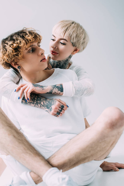 gaie fille étreignant petit ami avec les cheveux bouclés isolé sur gris
 - Photo, image
