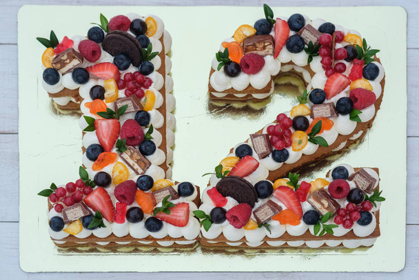 belo bolo de aniversário na forma do número doze em um substrato dourado vista superior
 - Foto, Imagem