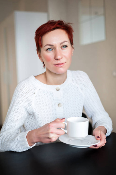 Жінка п'є каву вранці, за табуретом
 - Фото, зображення