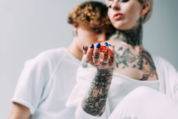 szelektív összpontosít, a tetovált lány piros kocka közeli barátja elszigetelt szürke gazdaság - Fotó, kép