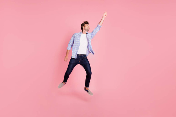 Full length body size photo of jumping high crazy he his him handsome holding umbrella in arm unbelievable flight wearing casual jeans checkered plaid shirt isolated on rose background - Foto, Bild