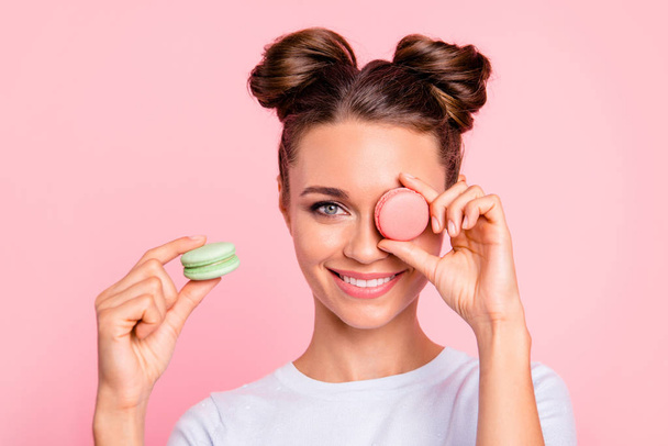 Close-up view of nice attractive funny girlish cheerful girl closing one eye with sugary colorful yummy tasty delicious pies confection isolated over pink background - Photo, image