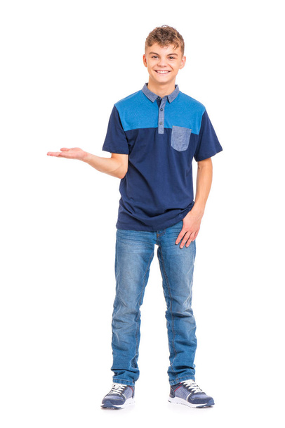 Full length portrait of teen boy holding something imaginary on palm, isolated on white background. Funny teenager showing copyspace on palm. Handsome child looking at camera and smiling. - Fotó, kép