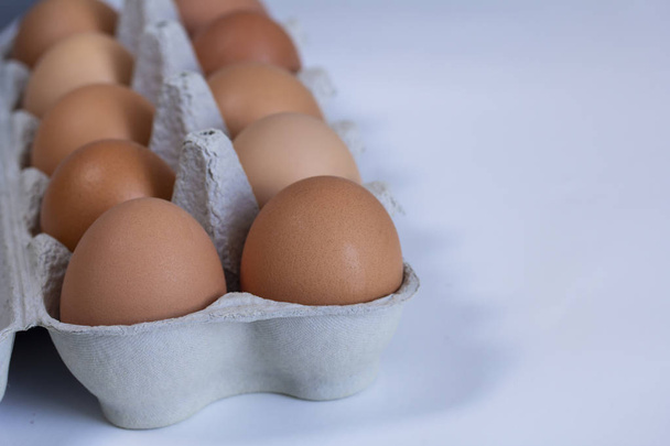 ruskeat kananmunat avoimessa pahvilaatikossa valkoisella pohjalla
 - Valokuva, kuva