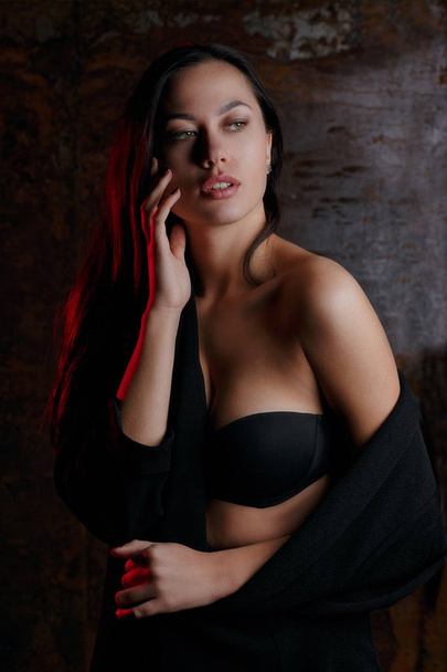 Studio portrait of young stylish woman wearing black lingerie, posing with red light - Fotó, kép