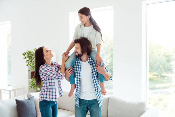 Portrait of nice lovely attractive cheerful cheery friendly people mom mum dad daddy carrying pre-teen girl having fun in modern white light interior room indoors - Fotó, kép