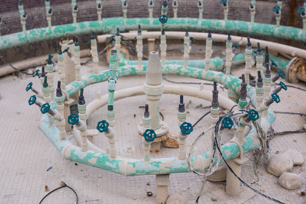 Sistema de ingeniería de tuberías y chorros de iluminación de una fuente drenada para mantenimiento o mantenimiento en un día de verano
 - Foto, imagen